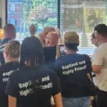 “Jesus Mission USA team praying with people during street outreach.”